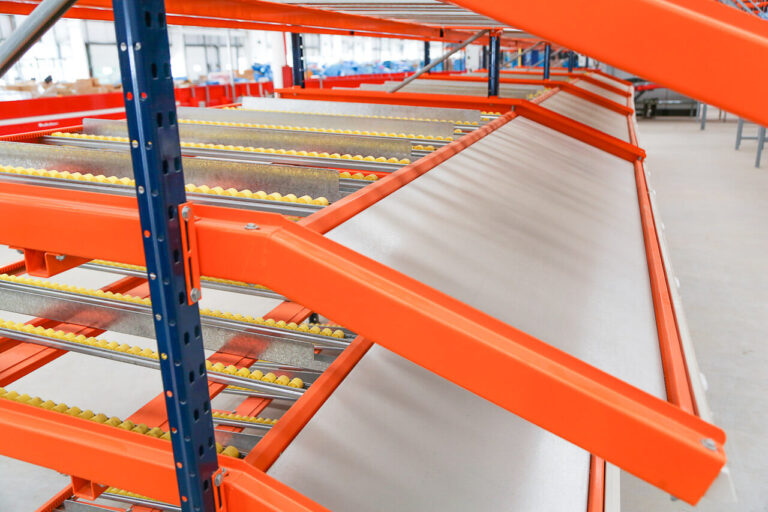 Sistema Flow Rack com trilhos inclinados e roletes para picking por gravidade (FIFO), representando eficiência operacional e redução do order cycle time.