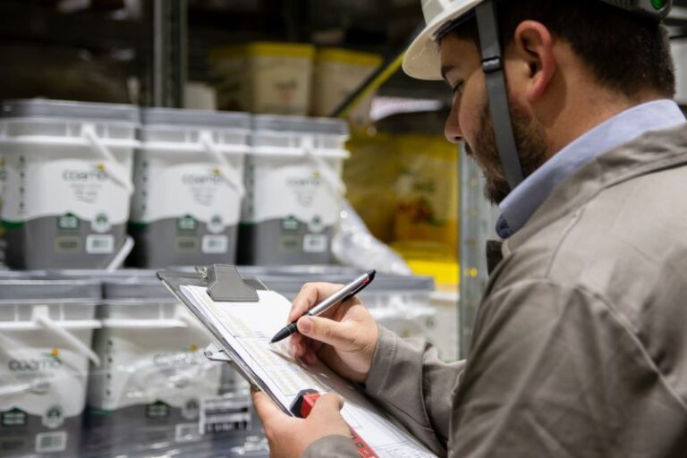 Operador conferindo palete em frente a estrutura porta-paletes em centro de distribuição.